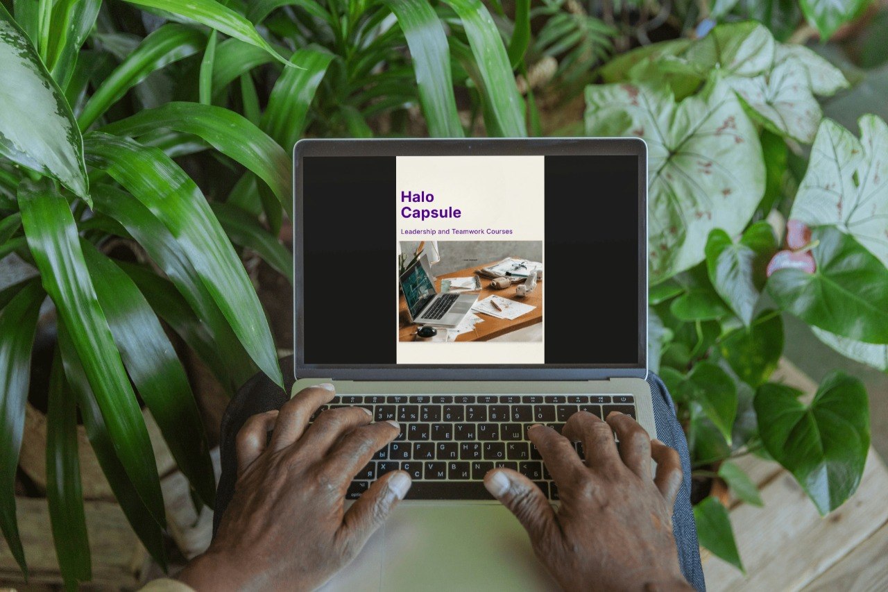Person using a laptop with a screen displaying 'Hello Capsule' in a green, leafy setting