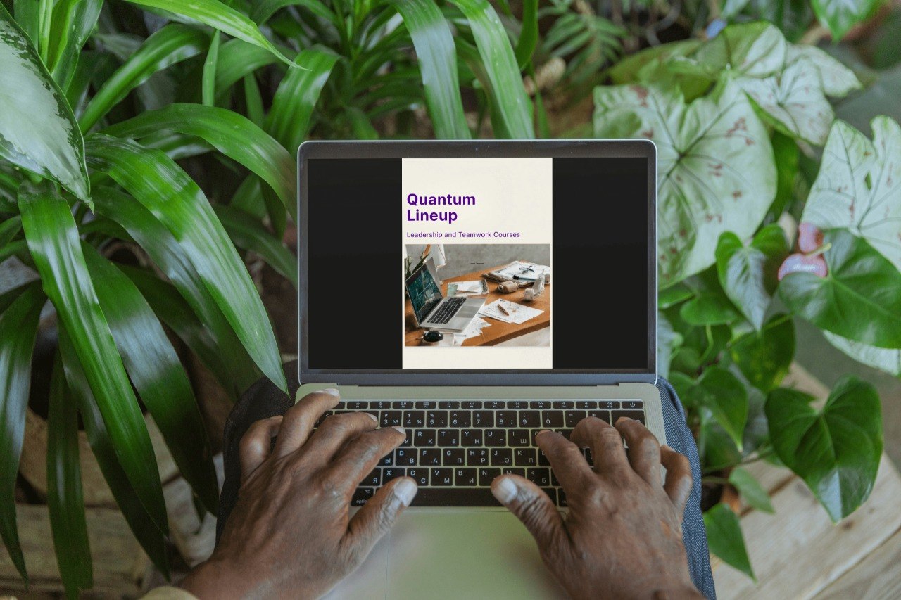 Person using a laptop with a 'Quantum Lineup' presentation on screen, surrounded by green plants.